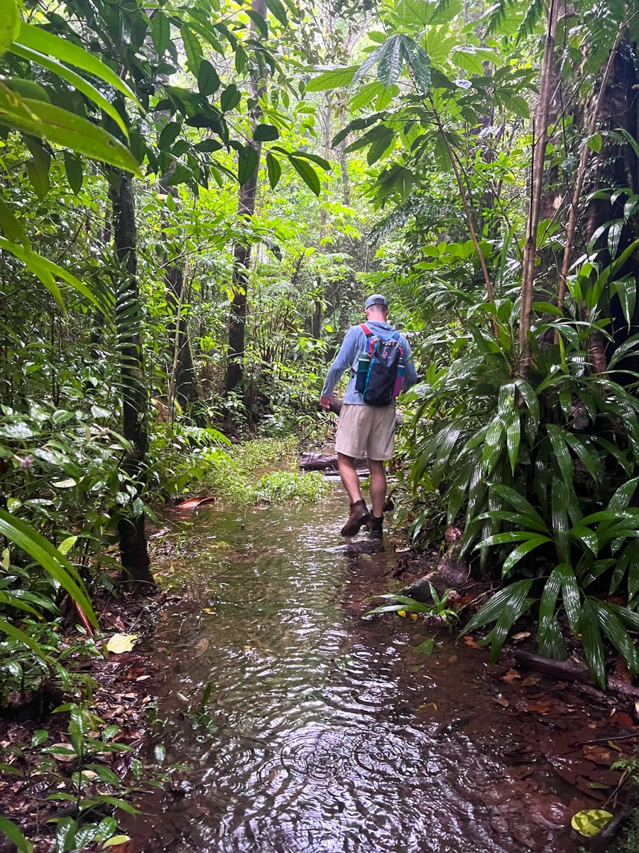 Man hiking on the trail to Middleham Falls with trail covered in inches of water
