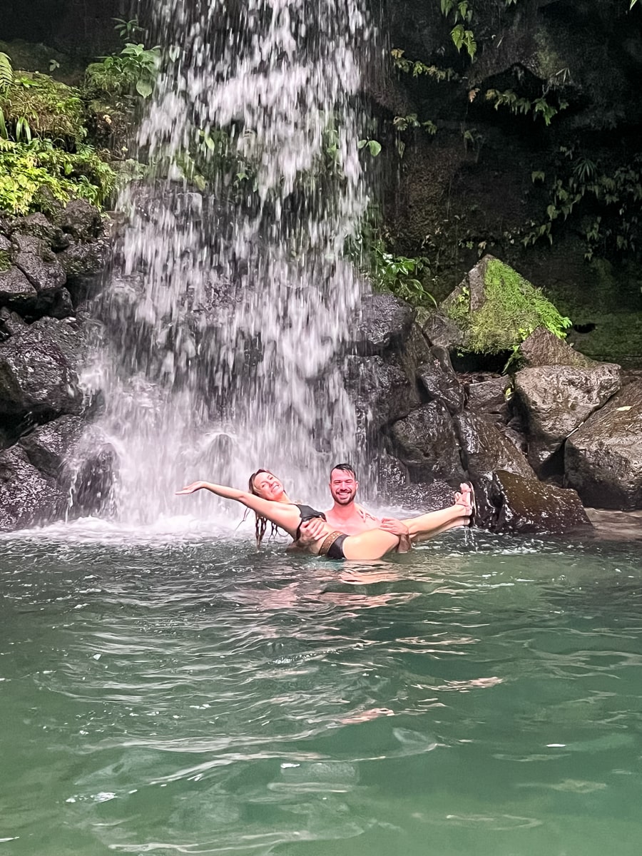 a couple standing underneath the falls at Emerald Pool 