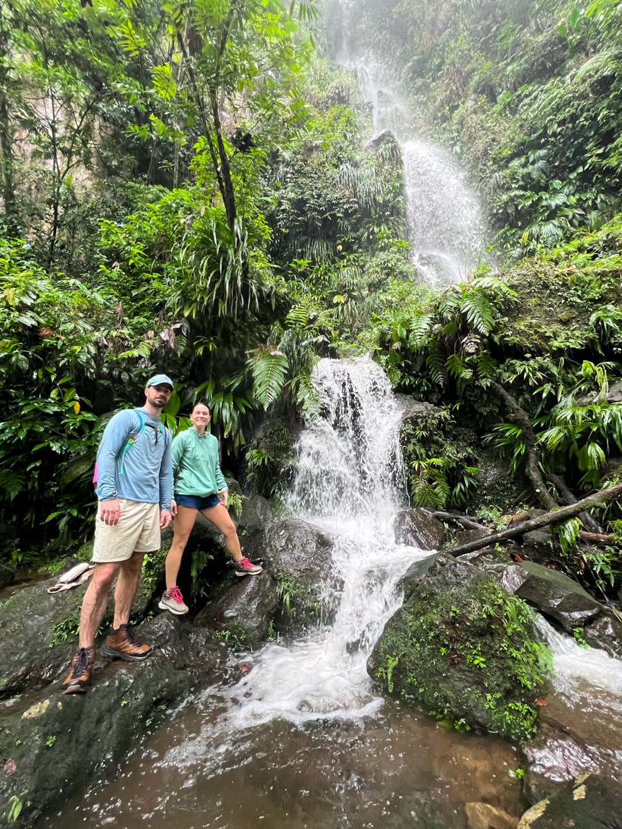 two people standing in front of a smaller waterfall near Middleham Falls