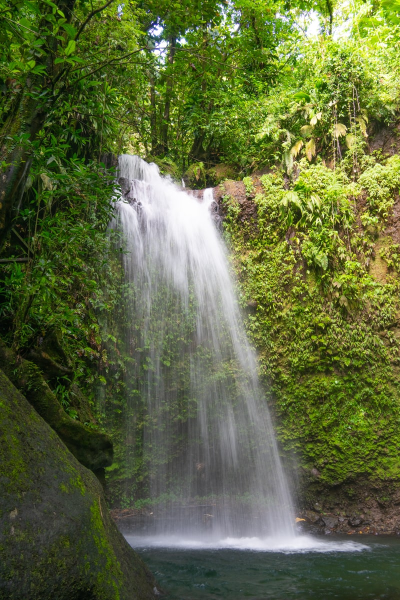 View of Salton Waterfalls from the base of the falls surrounded by cliffs of greenery