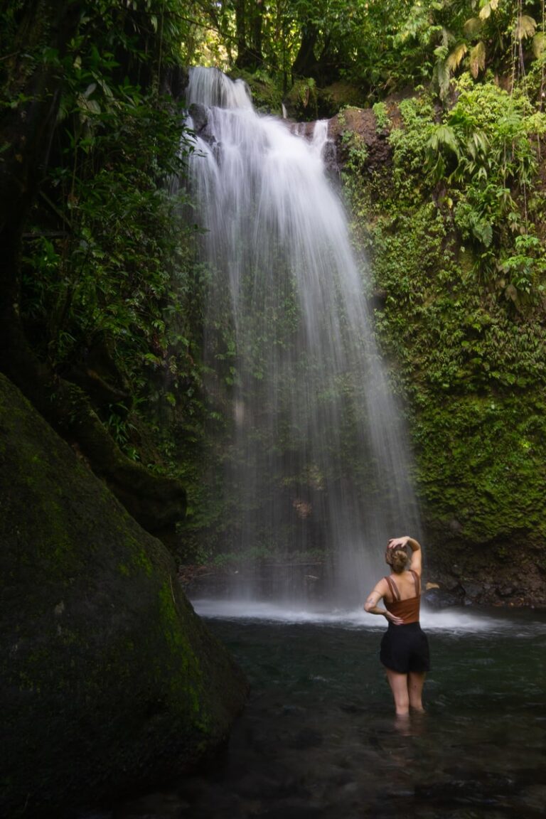 woman standing in the water in front of Salton Waterfalls by a large boulder