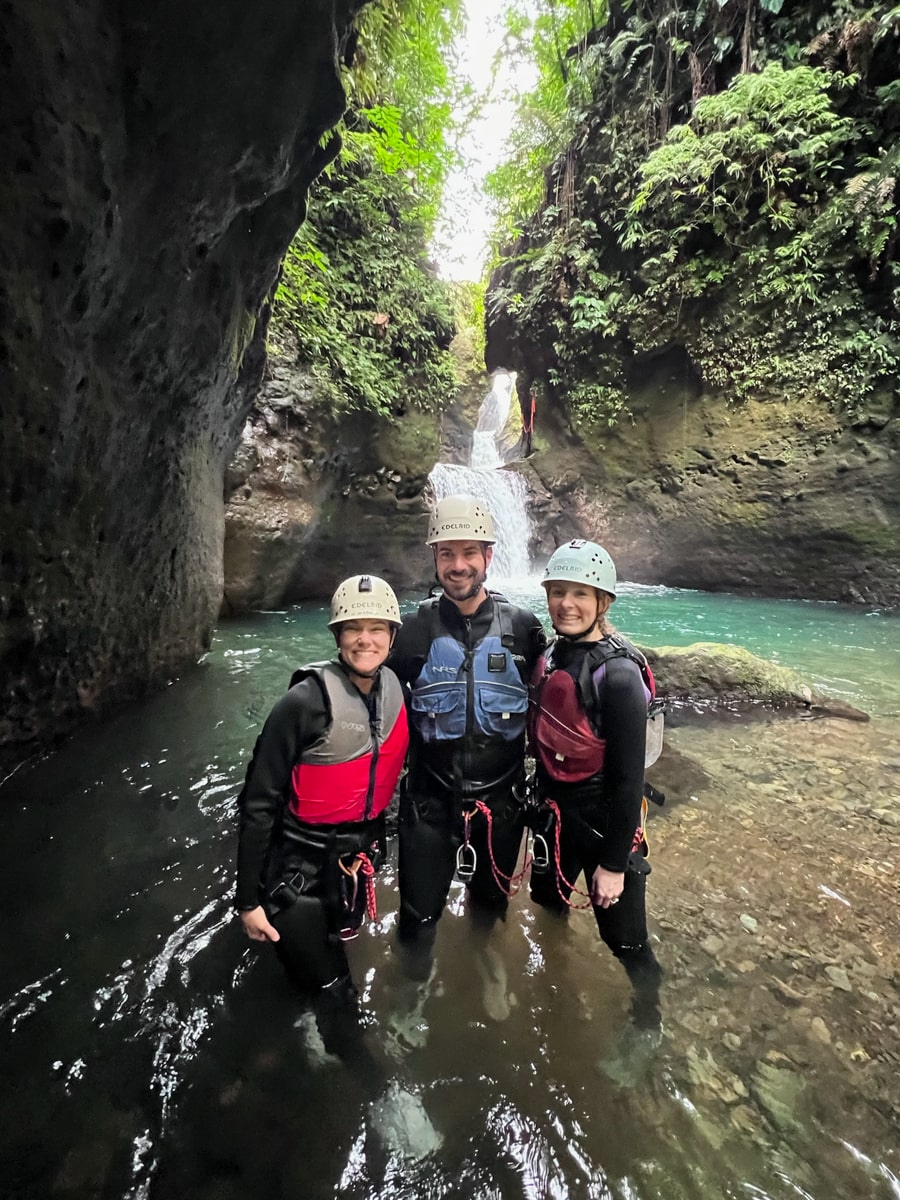 people standing in front of cathedral falls in Dominica in rappelling gear for a tour
