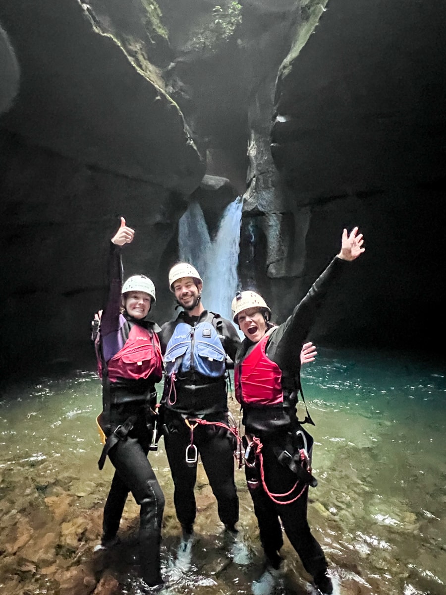 People in rappelling gear standing in front of Cathedral Falls in Titou Gorge in Dominica