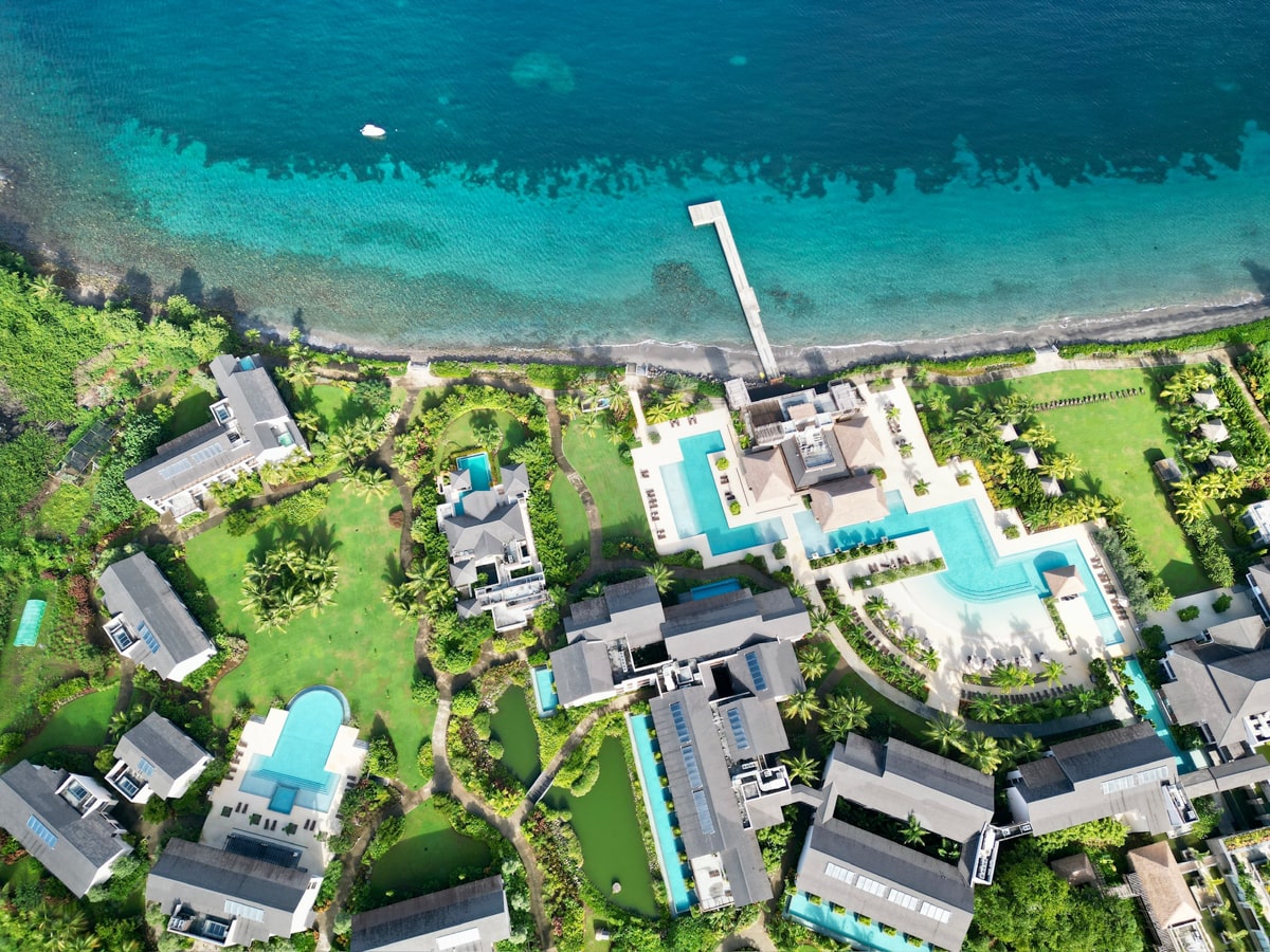 Drone view of the Intercontinental Dominica Cabrits Resort and Spa showing the resort and blue water from ocean