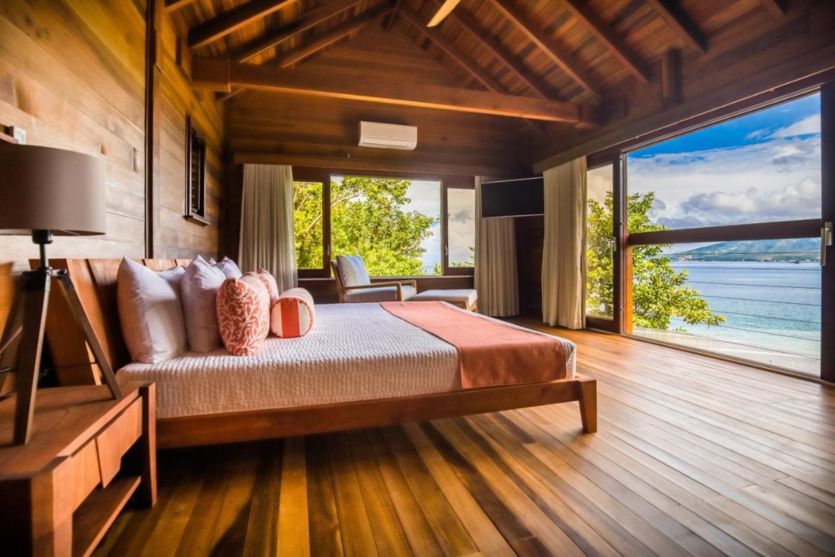 view of room at Secret Bay in Porstmouth of bed with an open balcony overlooking the Caribbean ocean