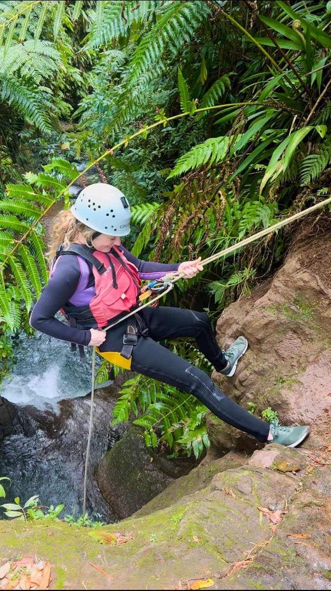 woman rappelling down a rock in titou gorge canyon