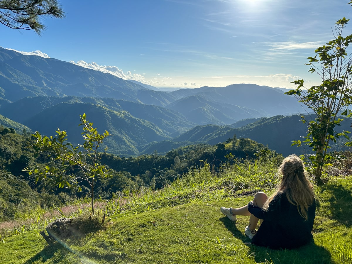 woman sitting on grass overlooking the blue mountains in Jamaica