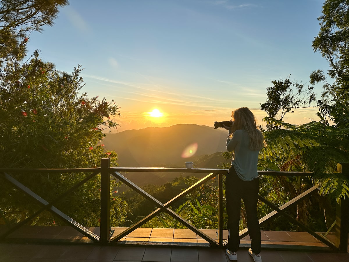 woman taking photos of the sunrise over the Blue Mountains in Jamaica