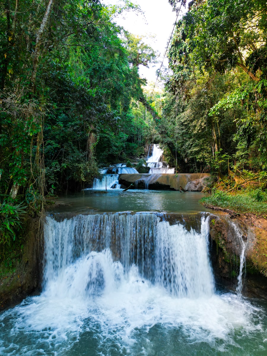 drone footage of YS falls with multiple tier waterfalls surrounded by green foliage in jamaica