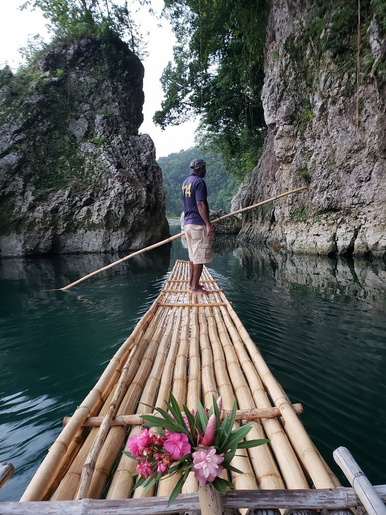 tour guide standing on a bamboo raft floating down the river in jamaica