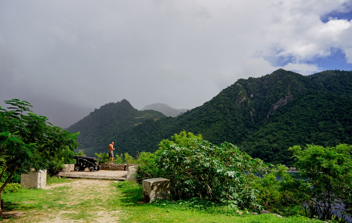 mountains that appear misty by clouds and man standing on a platform overlooking the oncoming storm in Dominica