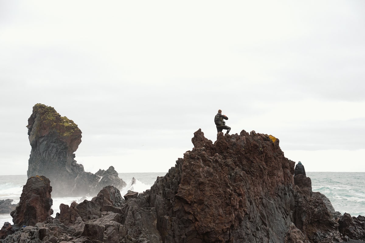 man standing on a lava formation overlooking the ocean on Djúpalónssandur Beach in Snaefellsnes Peninsula