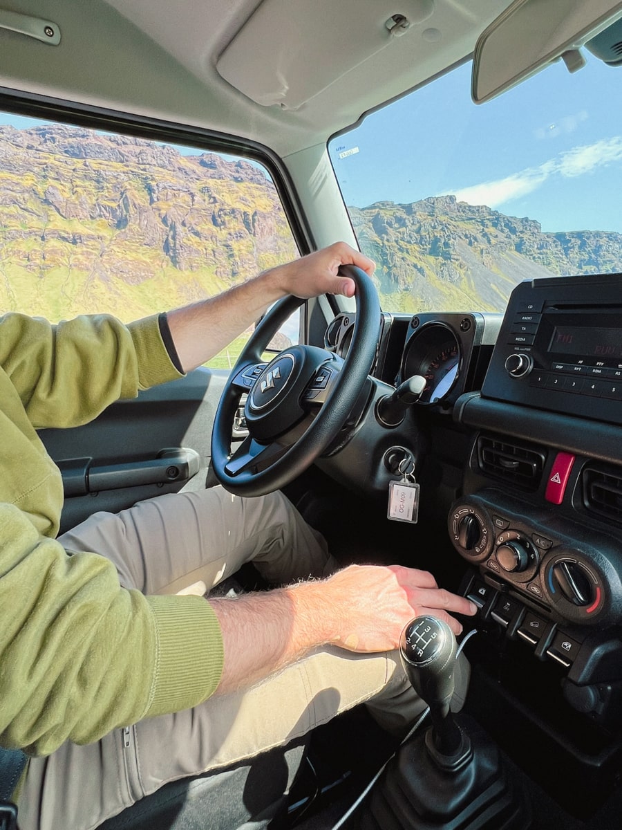 man driving a Suzuki Jimny rental car in Iceland with images of the Icelandic Highlands through the car window