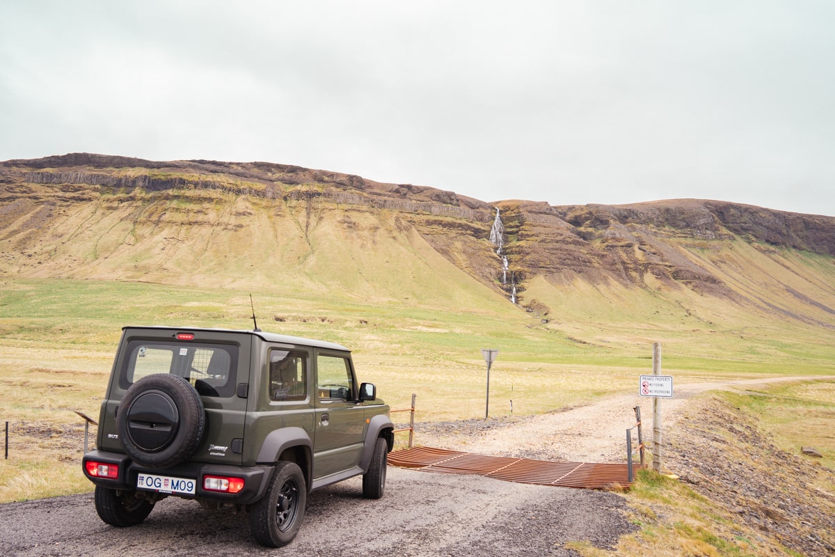 A suzuki Jimny car sitting on the road with the Icelandic highlands in teh background