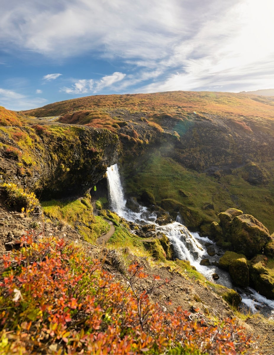 view of Selvallafoss waterfall from above with a blue sky and clouds 