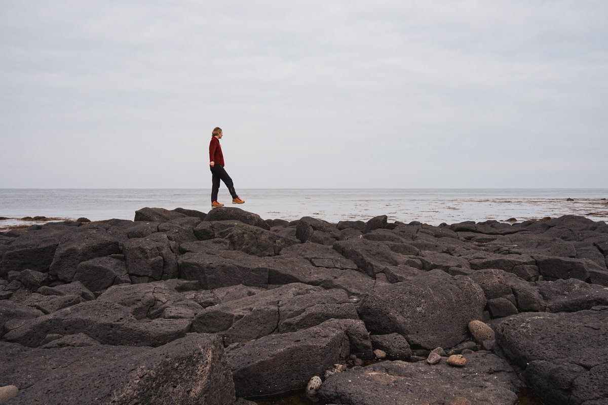 woman walking along the volanic rocks on the coast on the Snaefellsnes Peninsula in Iceland