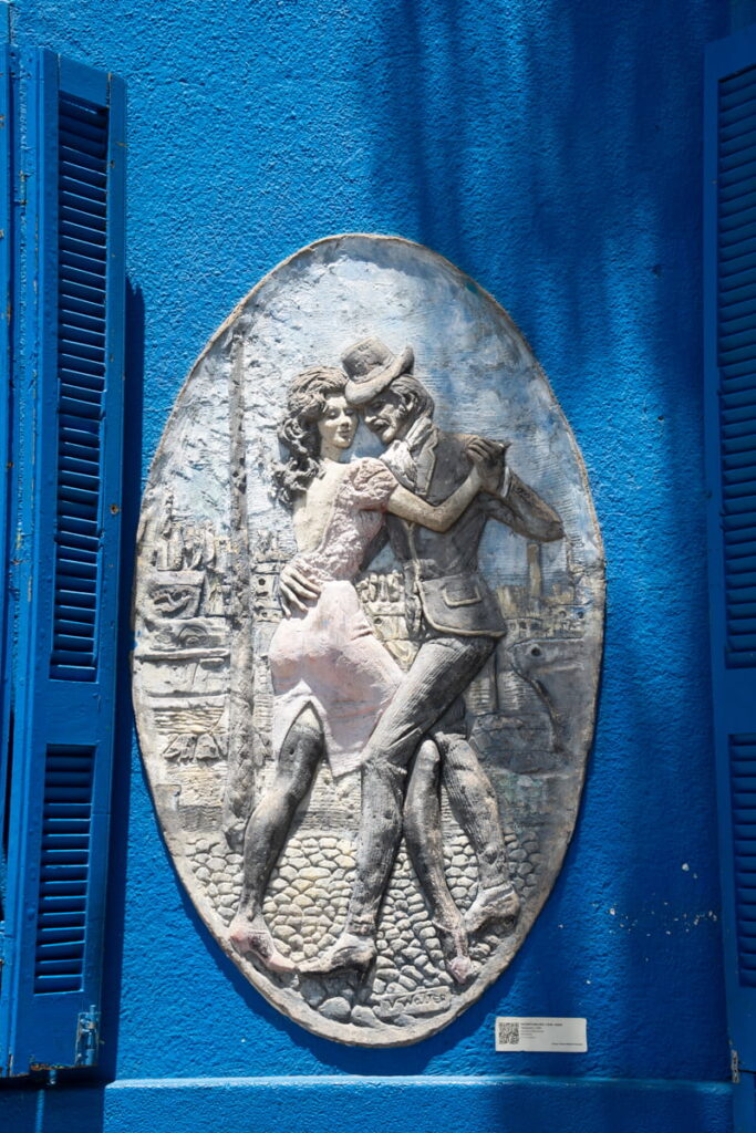 sculpture of people dancing the tango on a blue wall in Buenos Aires Argentina