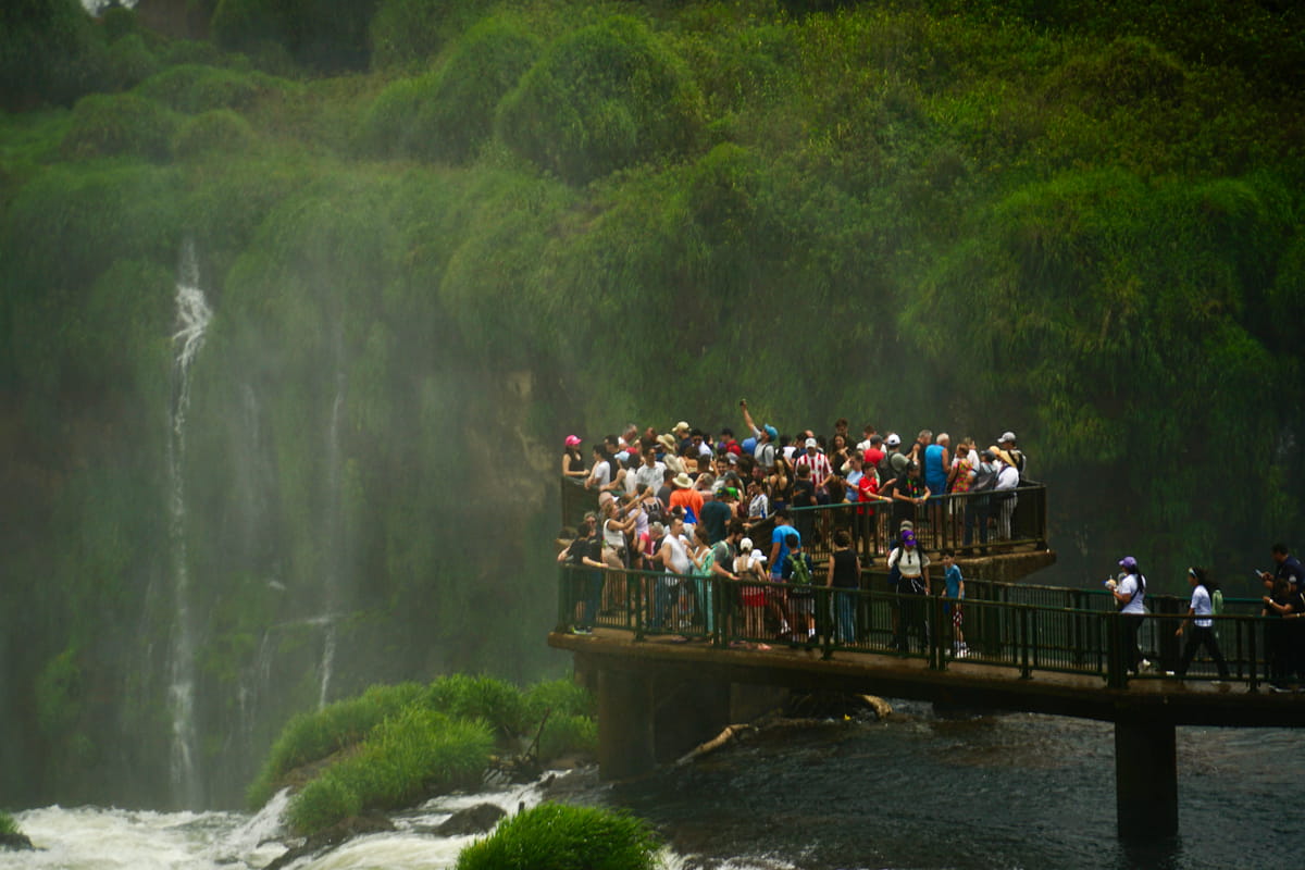 people standing on the boardwalk overlooking Iguazu falls