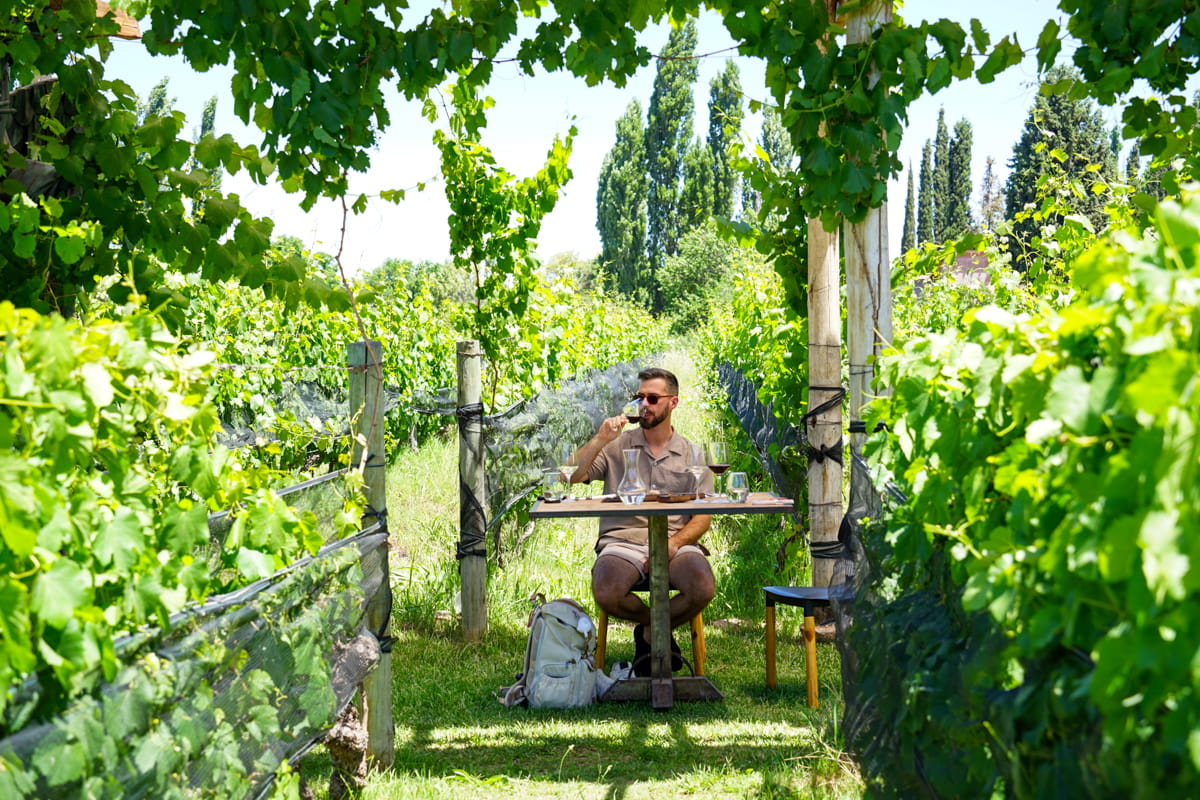 man drinking wine at a table in the vineyard of Finca Minimal winery in Mendoza Argentina