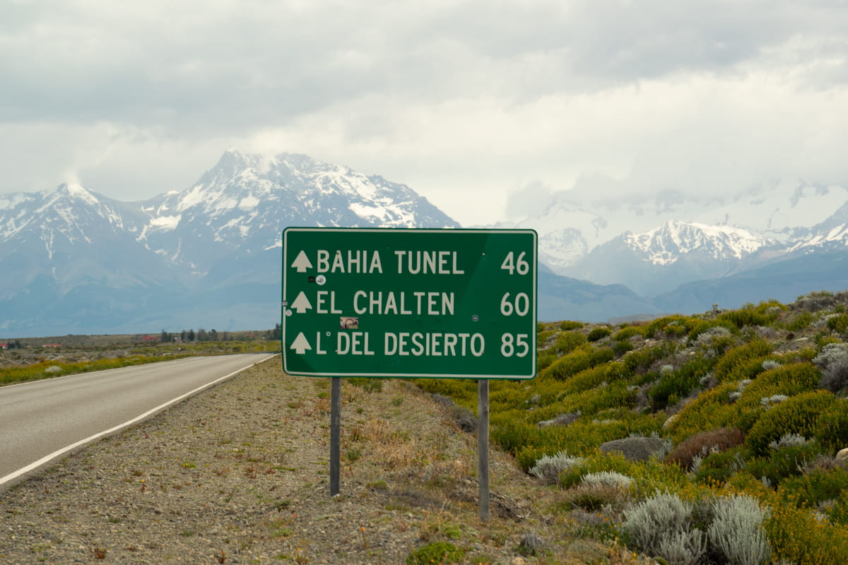 sign to El Chalten with views of the Patagonia mountains in the background