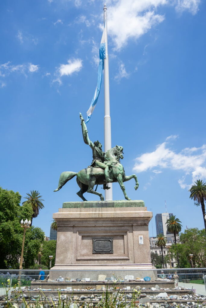 man riding on horse statue in front of Argentinian flag in downtown buenos aires argentina