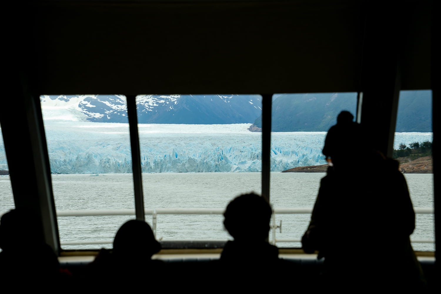 People looking through a window on the boat overlooking the Perito Moreno Glacier