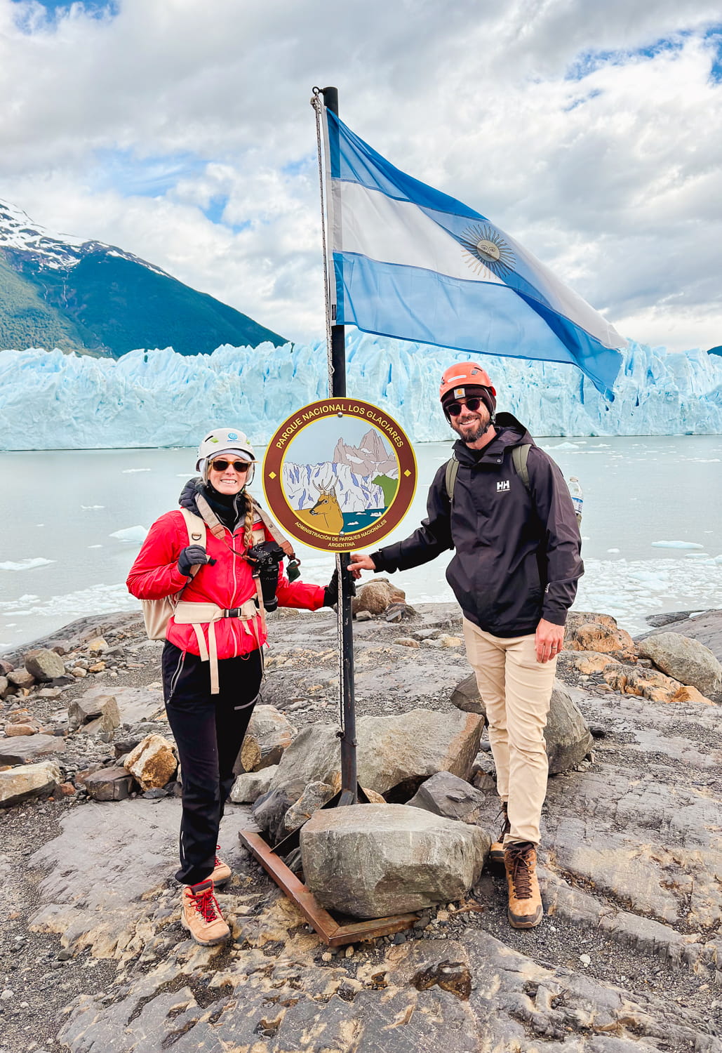 People standing underneath an Argentina flag at the base of the Perito Moreno glacier