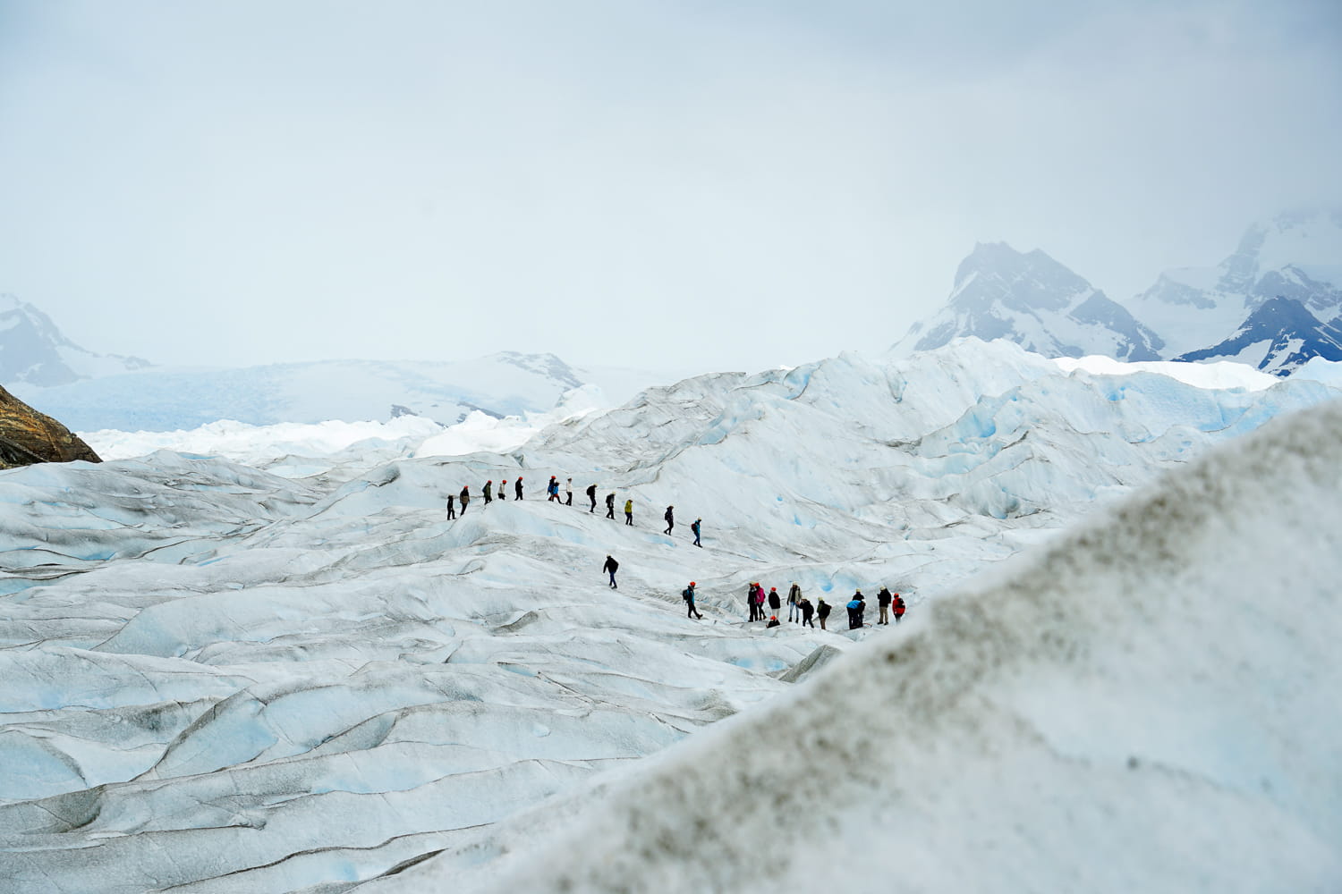A tour group of people trekking along the Perito Moreno glacier in the distance